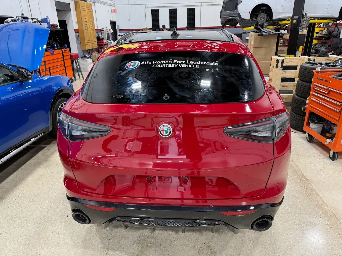Red Alfa Romeo SUV in a garage, rear view.