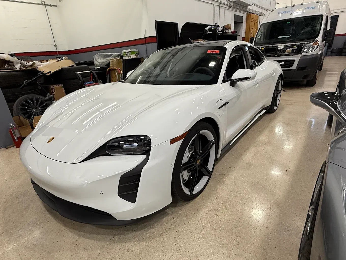 White Porsche Taycan electric car in a garage setting.