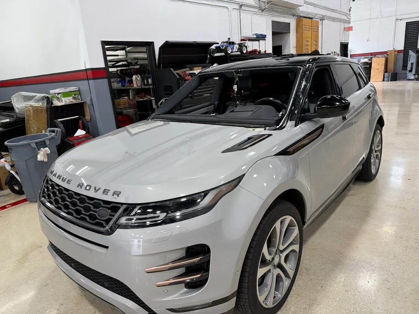 Silver Range Rover SUV in a garage. Black roof, silver wheels, setting with tools and equipment.
