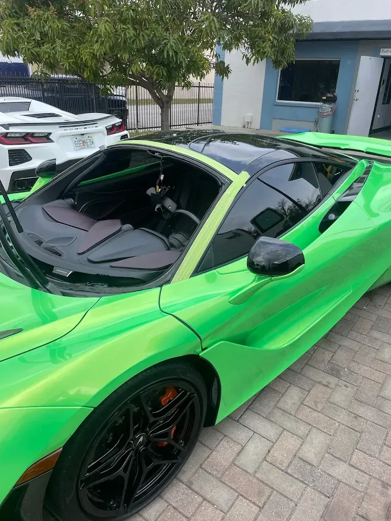 Bright green McLaren sports car with black accents and roof.