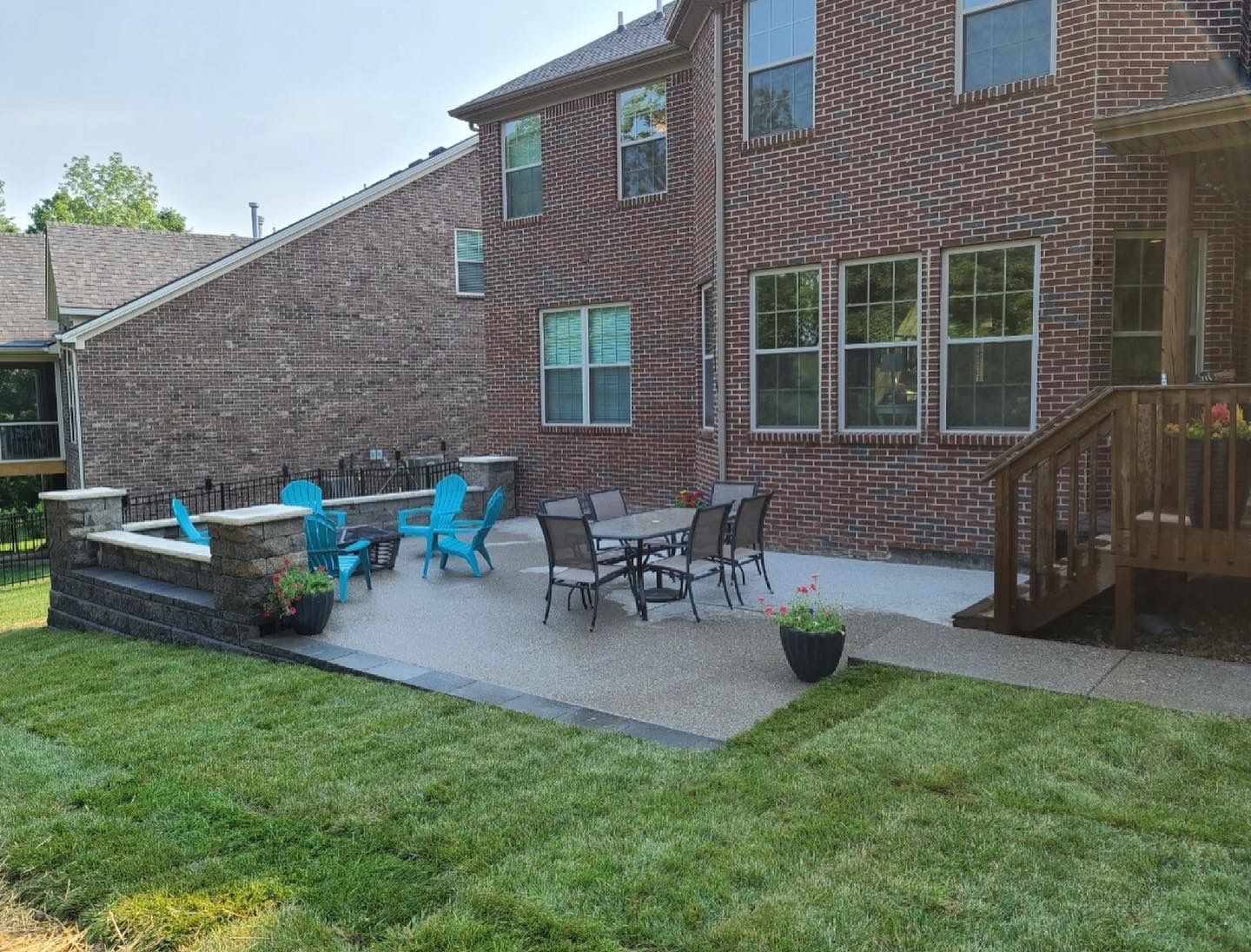 A patio with a table and chairs in front of a brick house.