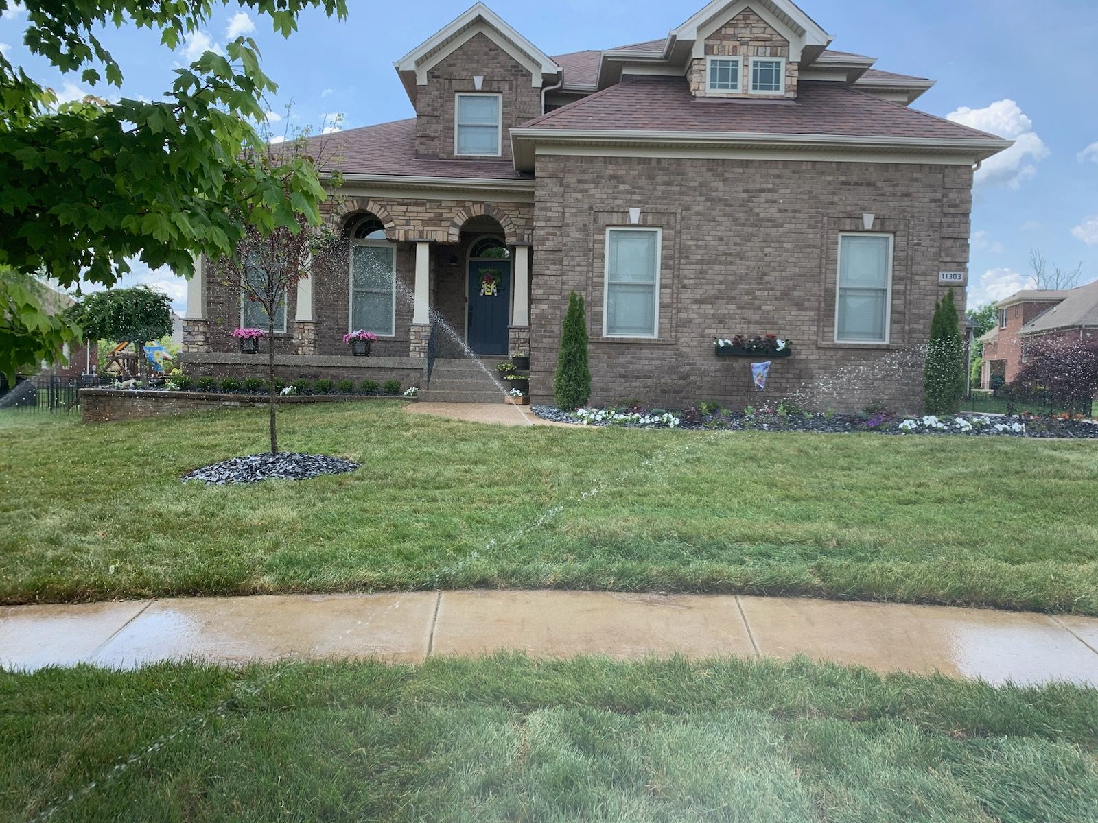 A large brick house with a lush green lawn in front of it.