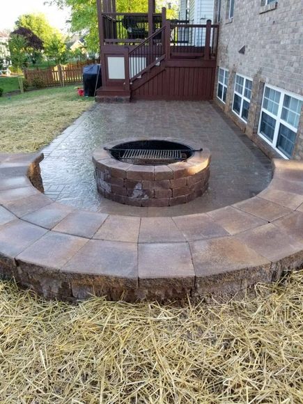 A fire pit is sitting on top of a patio next to a house.