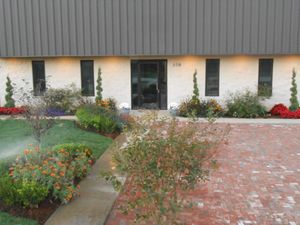 A white building with a brick driveway in front of it