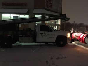 A snow plow is parked in front of a pharmacy