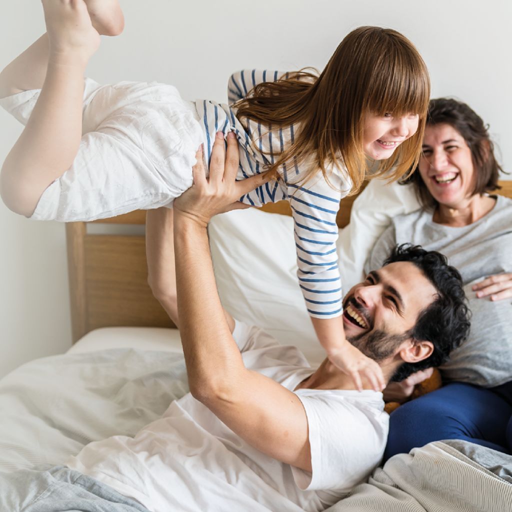 A man is holding a little girl up in the air.