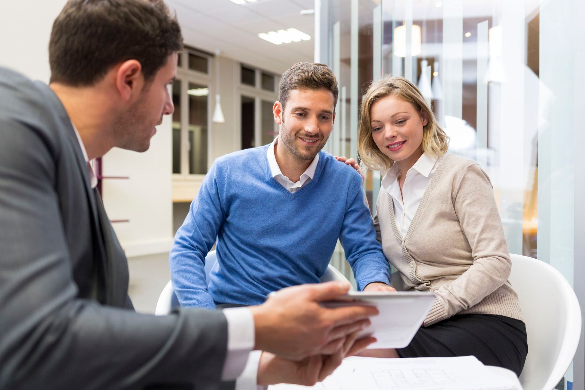 A man and woman are sitting at a table looking at a tablet.