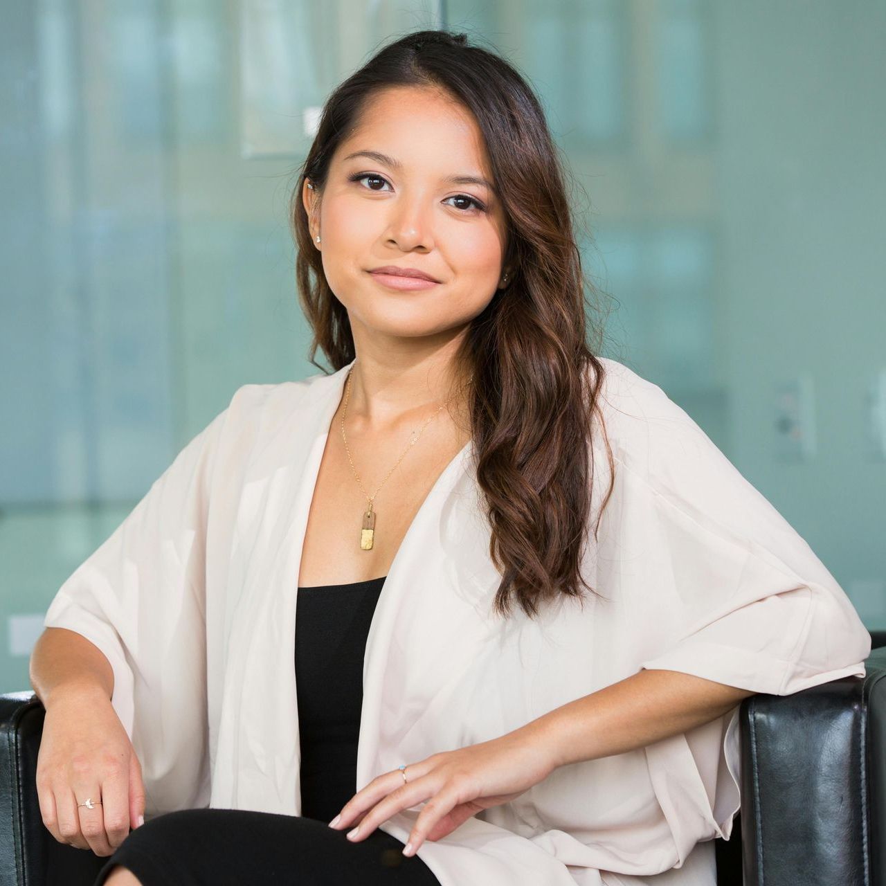 A woman is sitting in a chair with her arm resting on her lap.
