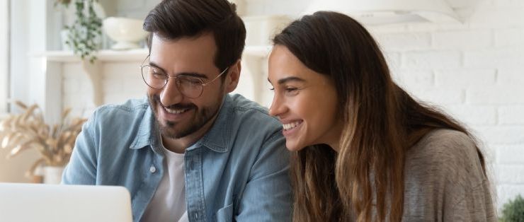 A man and a woman are looking at a laptop computer together.