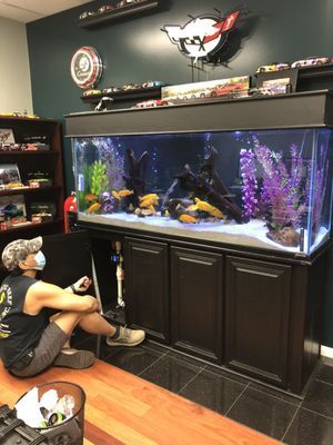 A man is sitting in front of a large fish tank.