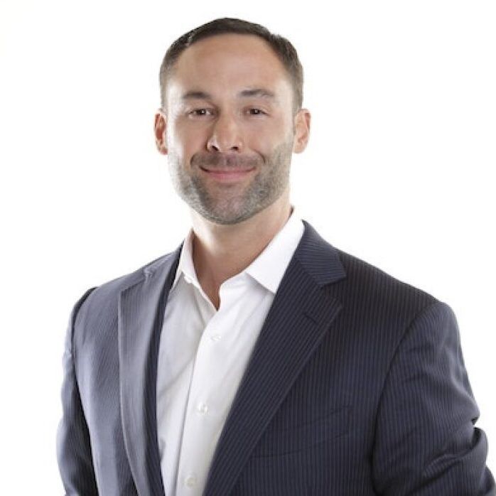 A man in a suit and white shirt is smiling for the camera.