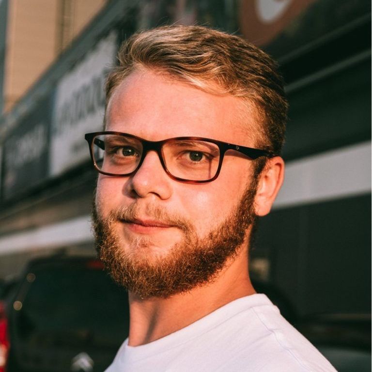 A man with a beard wearing glasses and a white shirt