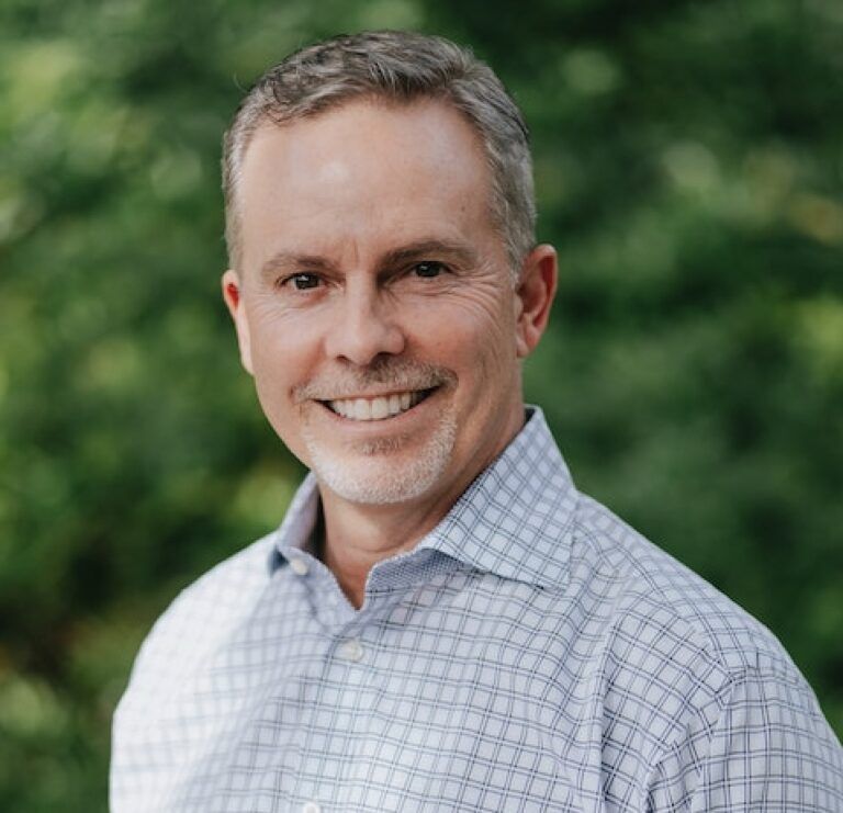 A man in a plaid shirt is smiling for the camera.