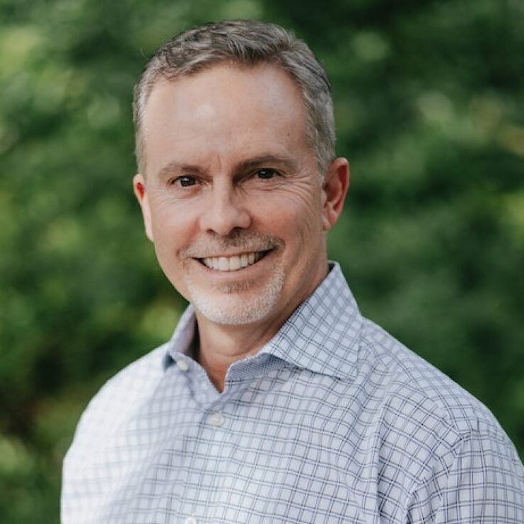 A man in a plaid shirt is smiling for the camera.