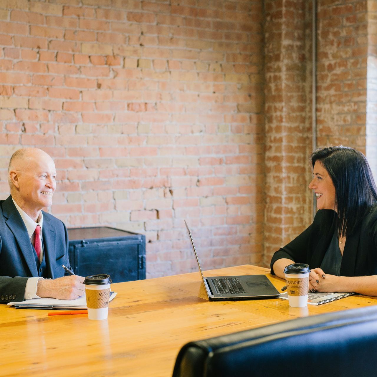 A man and a woman are sitting at a table talking to each other.