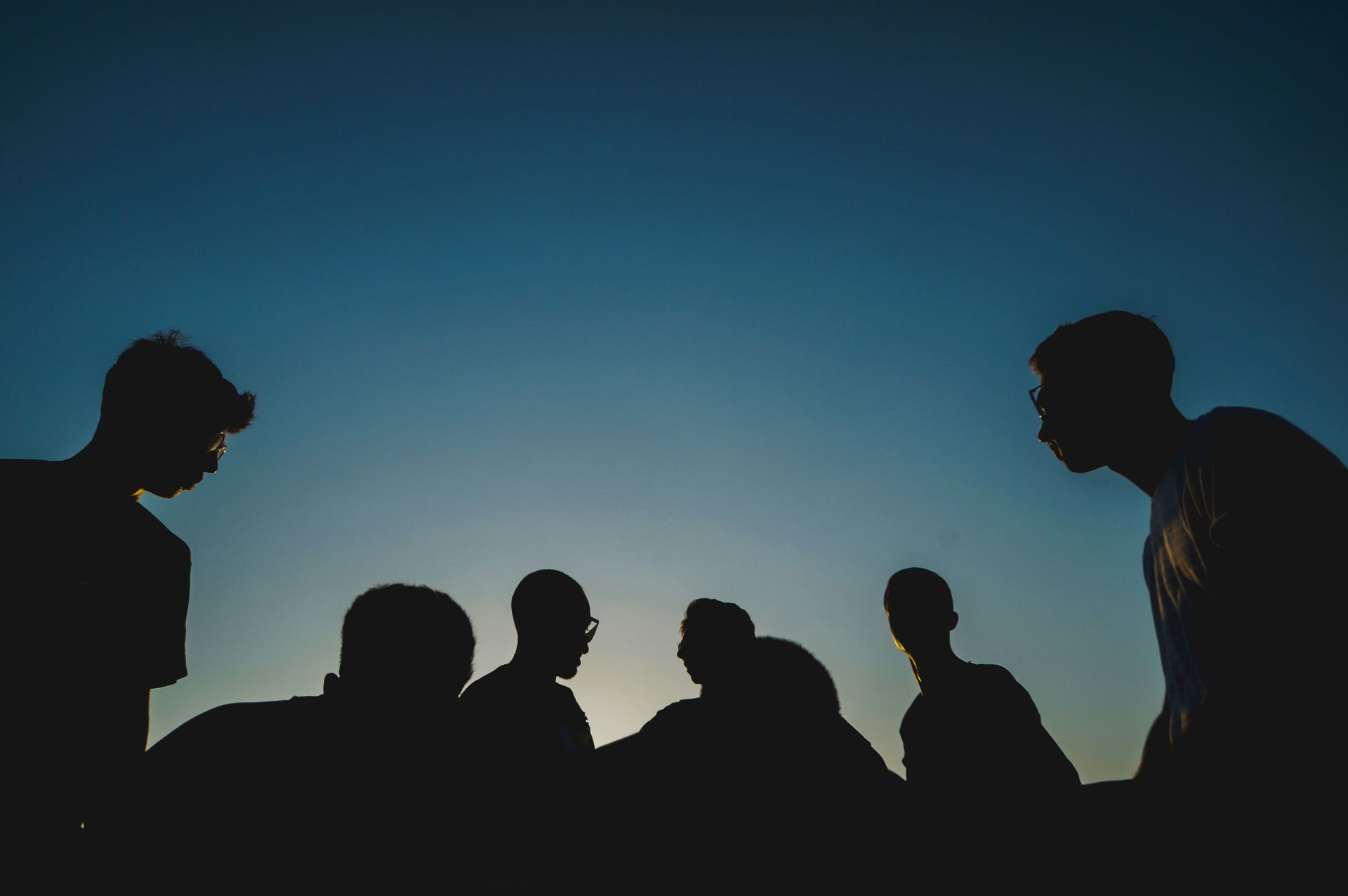 A group of people are standing next to each other in front of a blue sky.