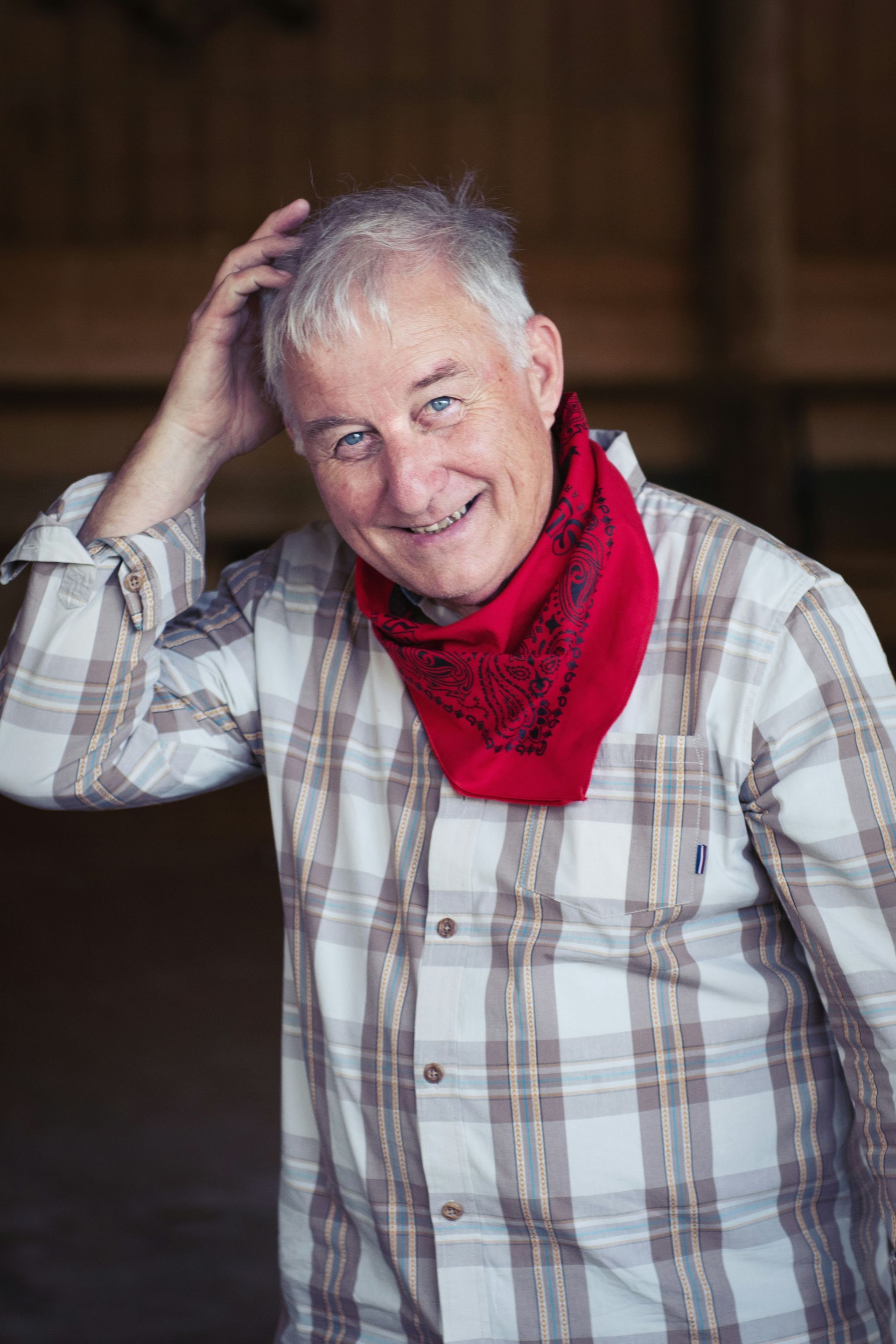 The man is wearing a plaid shirt and a red bandana around his neck.