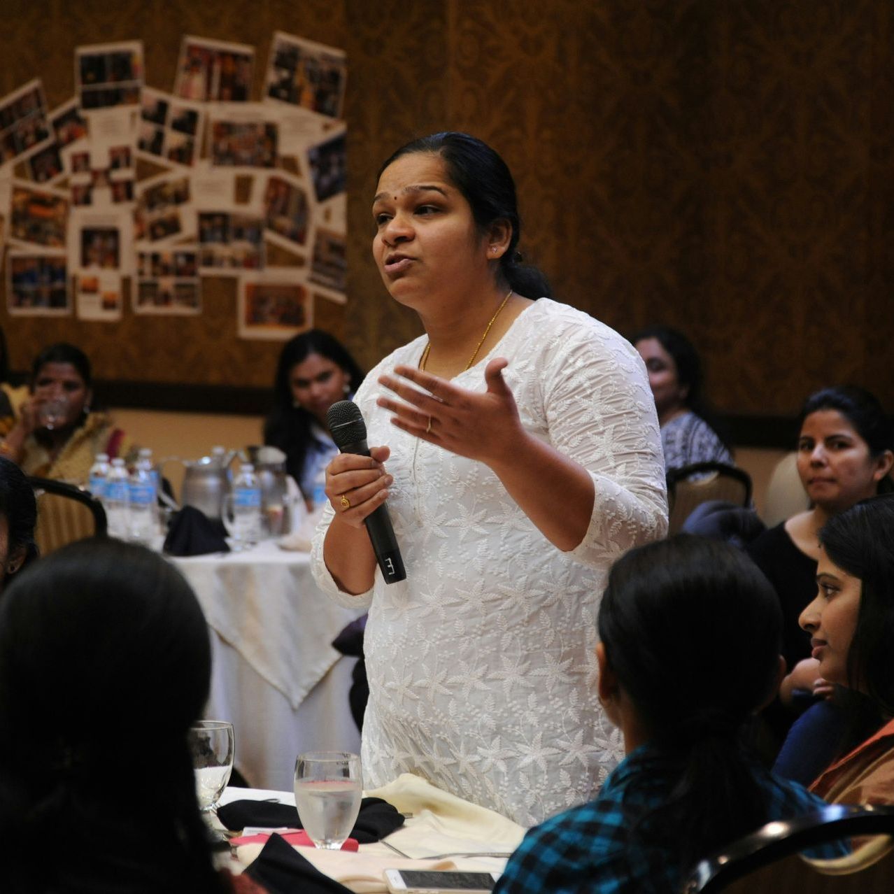 A woman speaking into a microphone in front of a group of people