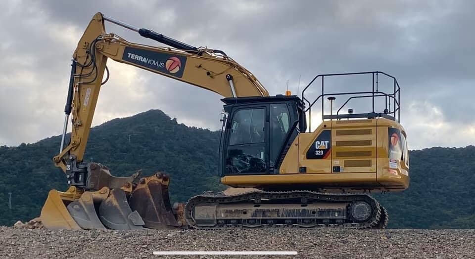 A Large Yellow Excavator Is Parked on A Gravel Road — Terranovus Earthworks & Plant Hire in Cairns, QLD