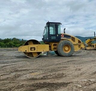 A Yellow Roller Is Sitting on Top of A Dirt Field — Terranovus Earthworks & Plant Hire in Cairns, QLD