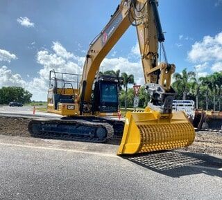 A Large Yellow Excavator Is Parked on The Side of A Road — Terranovus Earthworks & Plant Hire in Cairns, QLD