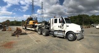 A white Semi truck is Carrying a Bulldozer on a Trailer — Terranovus Earthworks & Plant Hire in Cairns, QLD