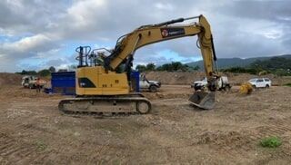 A Yellow Excavator Is Sitting on Top of A Dirt Field — Terranovus Earthworks & Plant Hire in Cairns, QLD