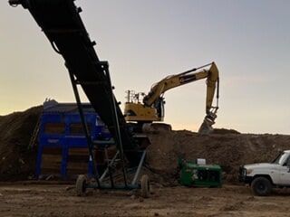 A Large Excavator Is Working on A Construction Site Next to A Truck — Terranovus Earthworks & Plant Hire in Cairns, QLD