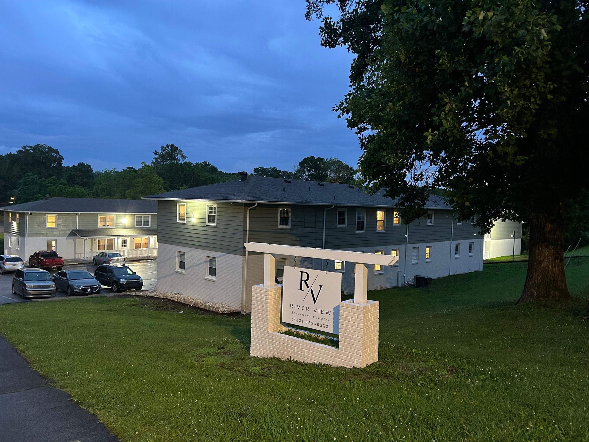 A building with a sign in front of it and cars parked in front of it.