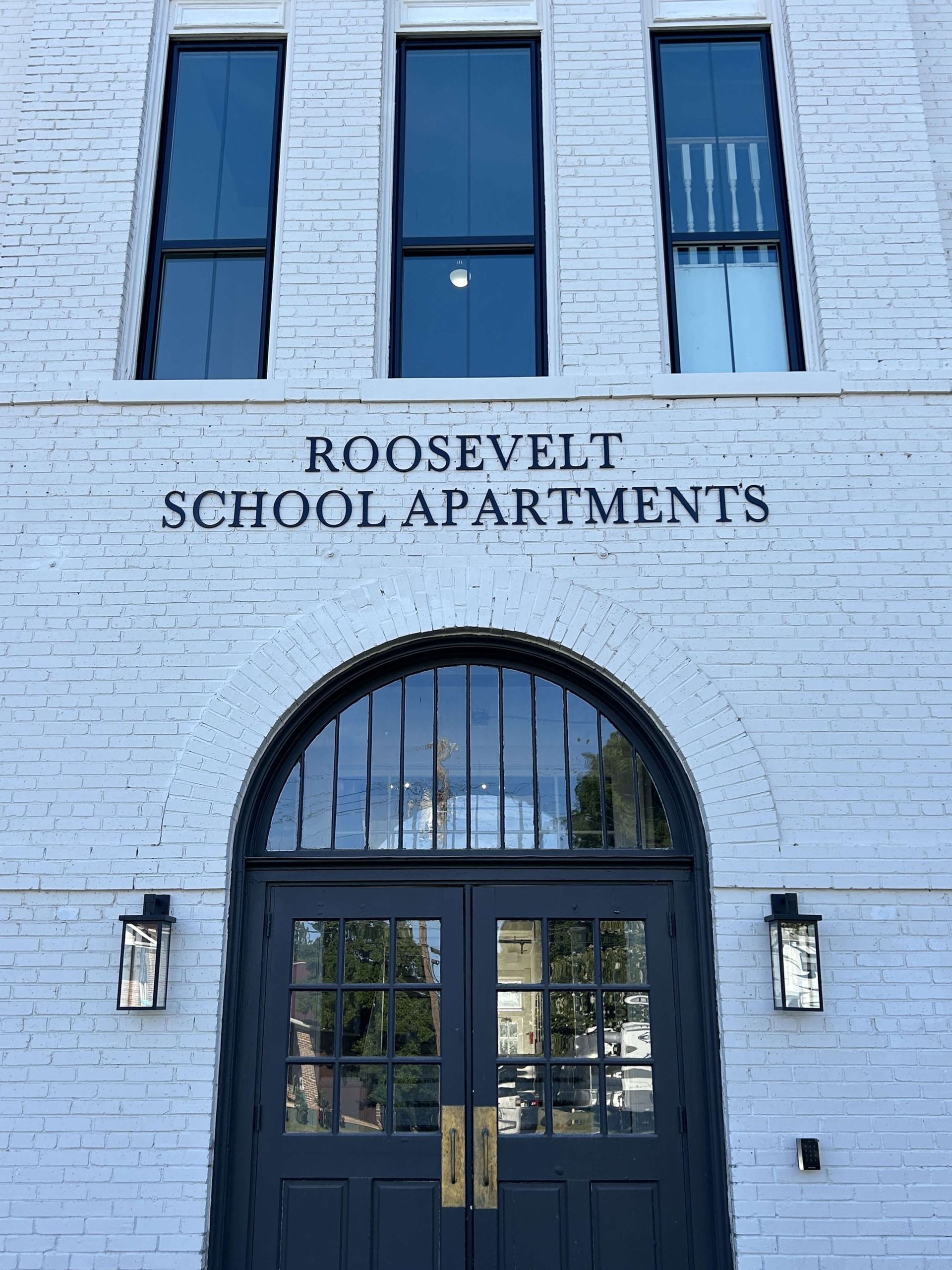 A white brick building with the words roosevelt school apartments on it