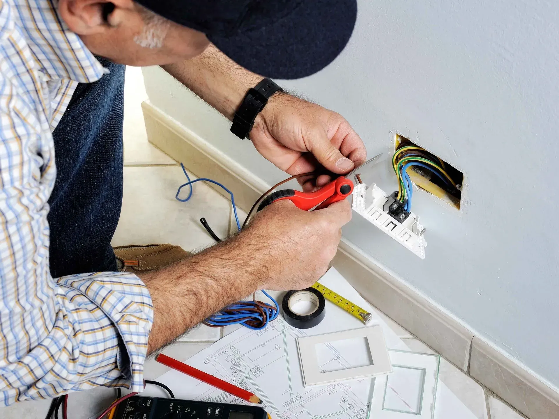 Electrician working on a wall outlet and holding a multimeter. Electrician working on a wall outlet and holding a multimeter.