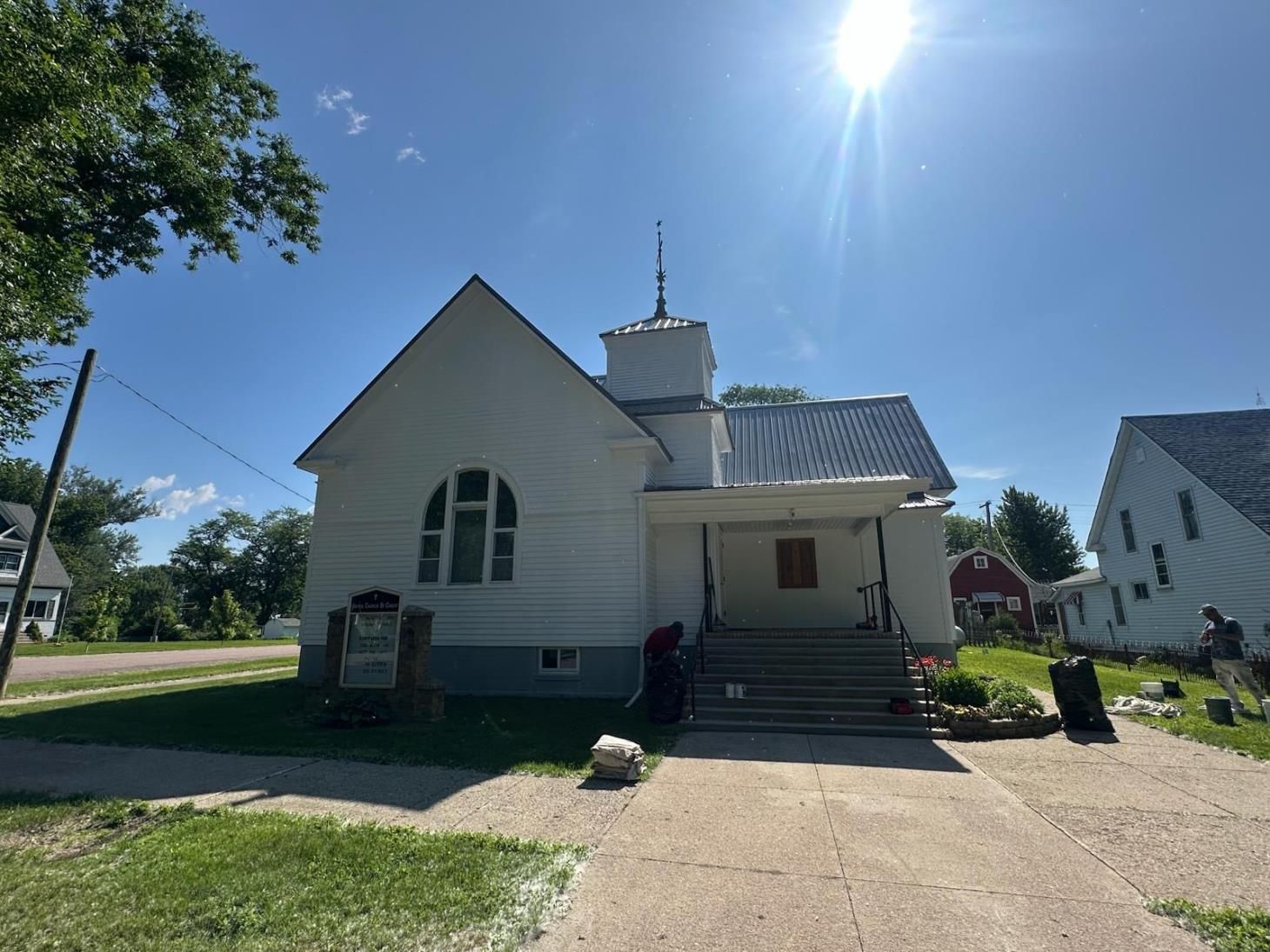 White church building with steeple, gray roof, and blue sky.