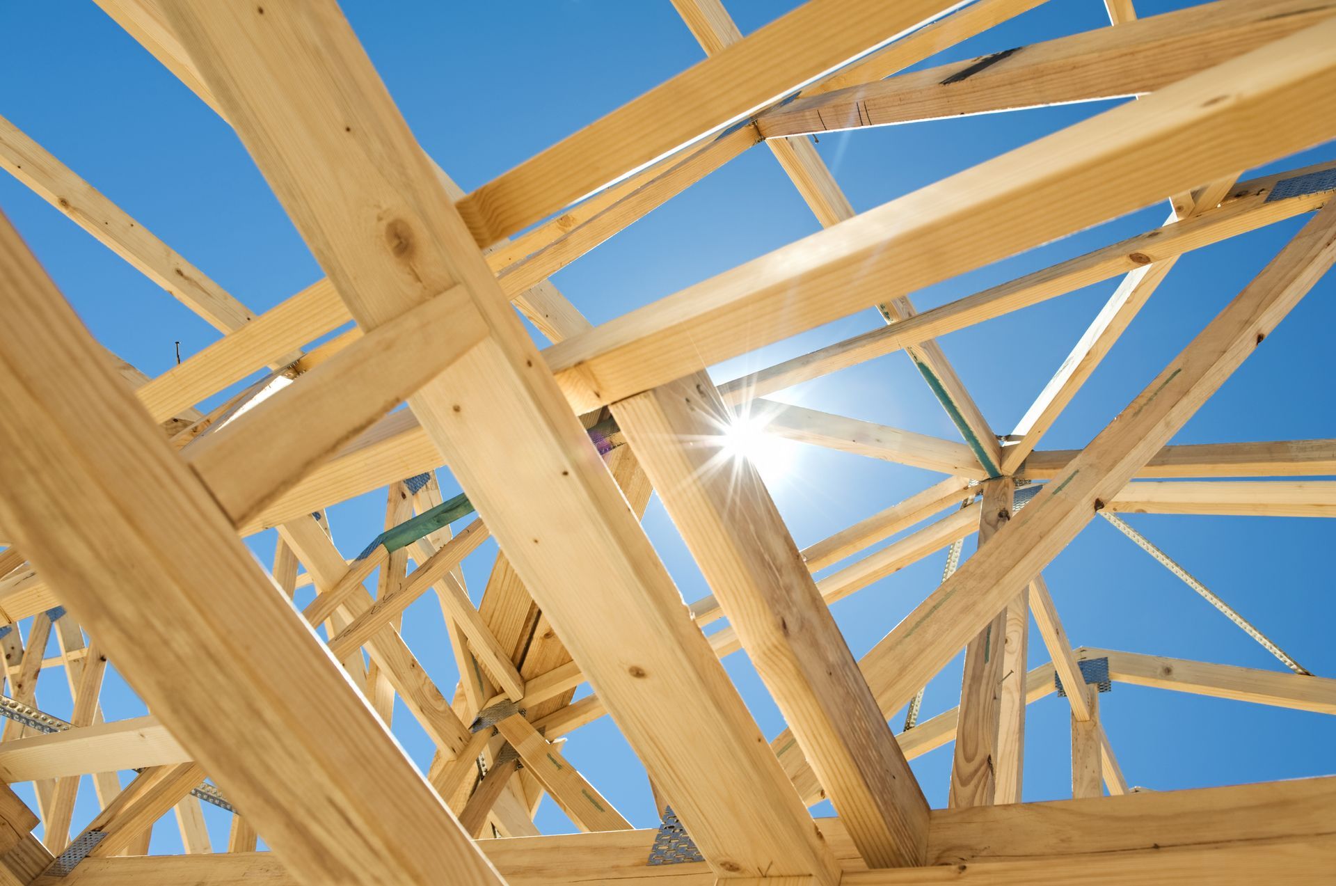 Wooden roof frame against a bright blue sky.