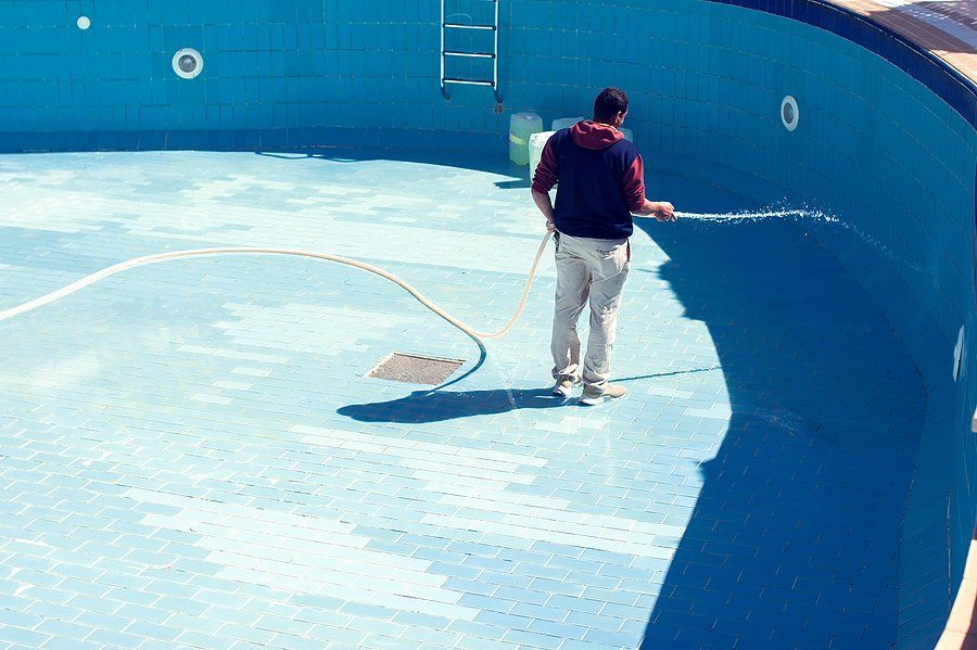 man cleaning the tile of the pool