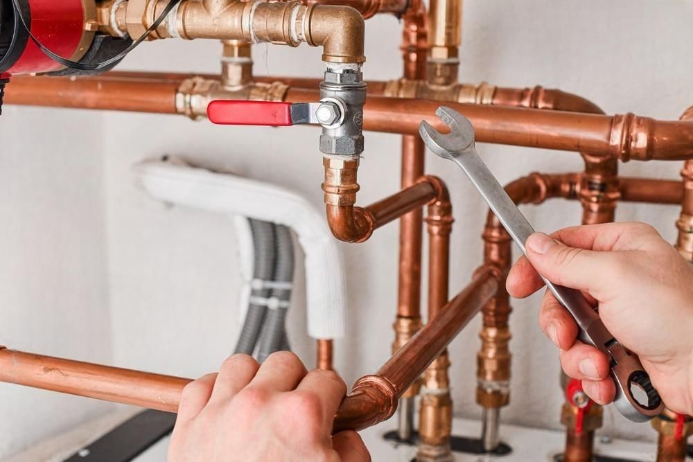 A person is fixing copper pipes with a wrench.