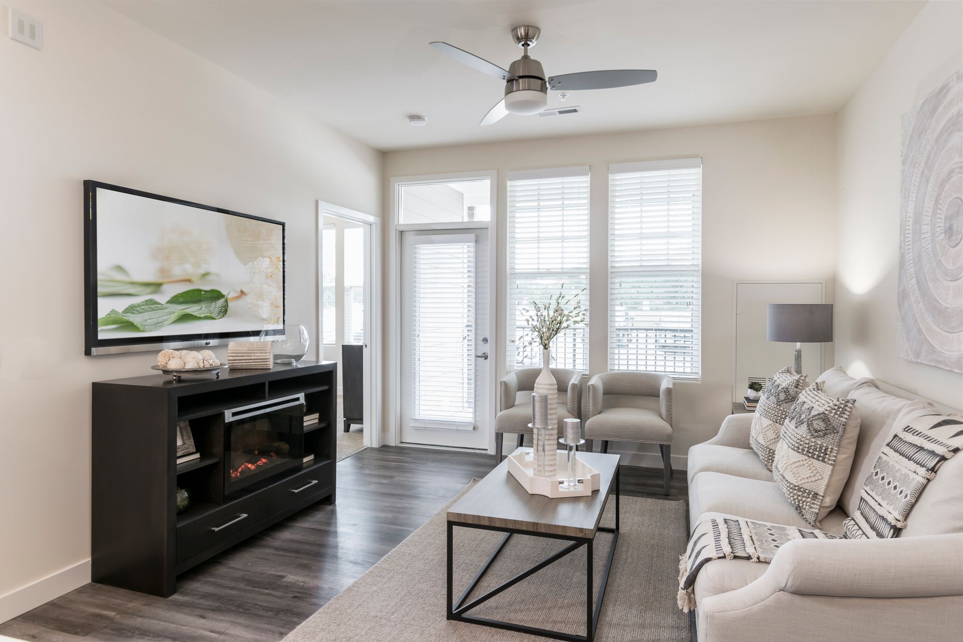Cozy living room with a fireplace, TV, white couch, chairs, and a door to a balcony.