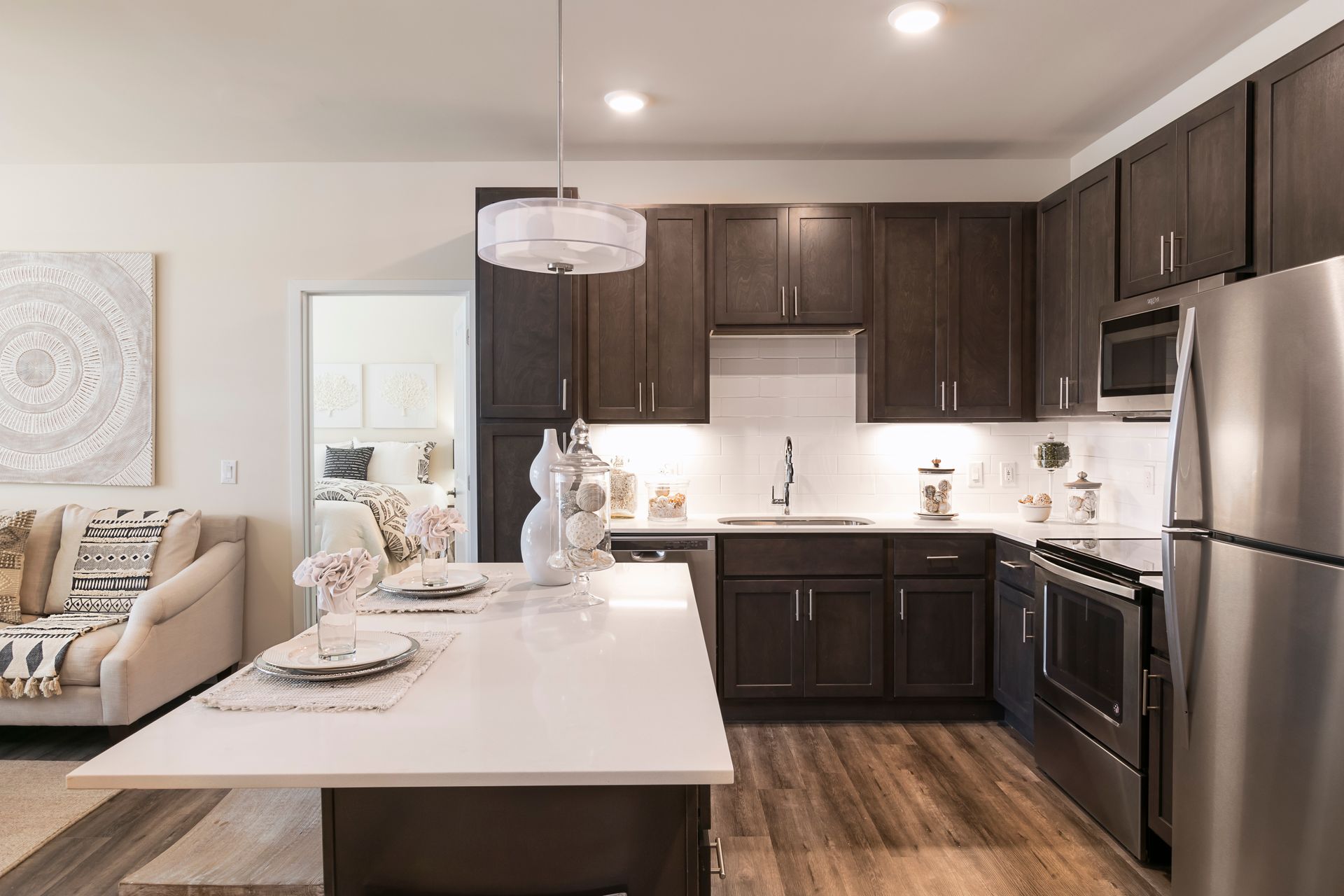 Modern kitchen with dark brown cabinets, white countertops, and stainless steel appliances.