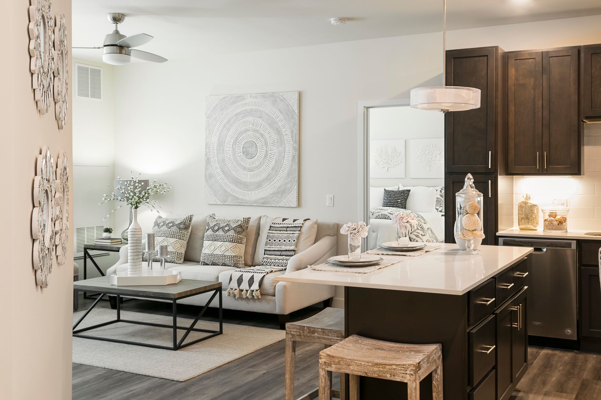 Open-concept living space with a kitchen island and a sofa. White walls, wood cabinets, and decor.