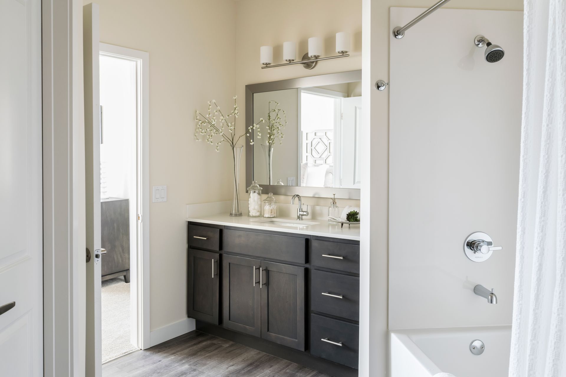 Bathroom with dark cabinets, a white shower, and a large mirror.