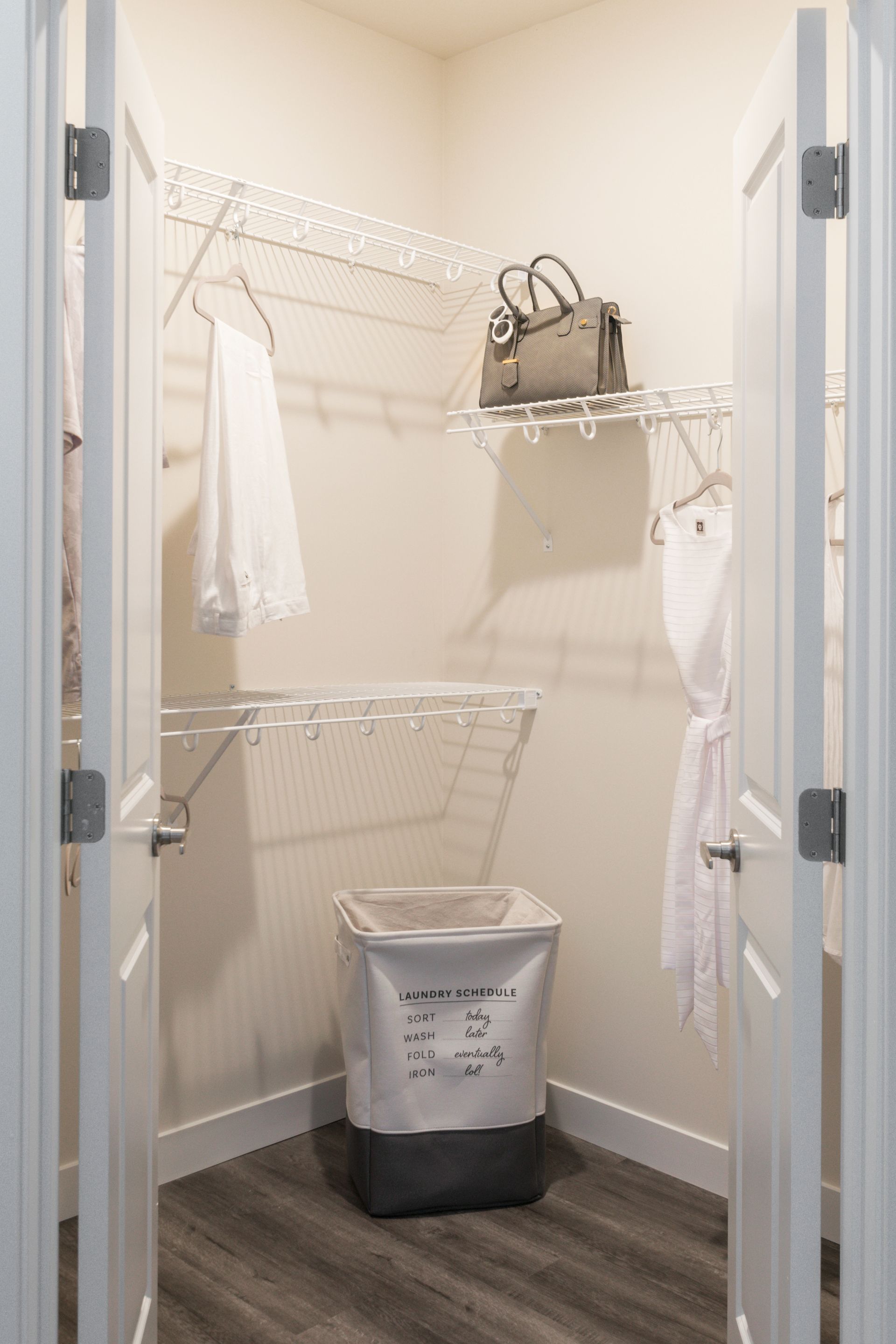 White closet with wire shelves, laundry bag, and clothes.