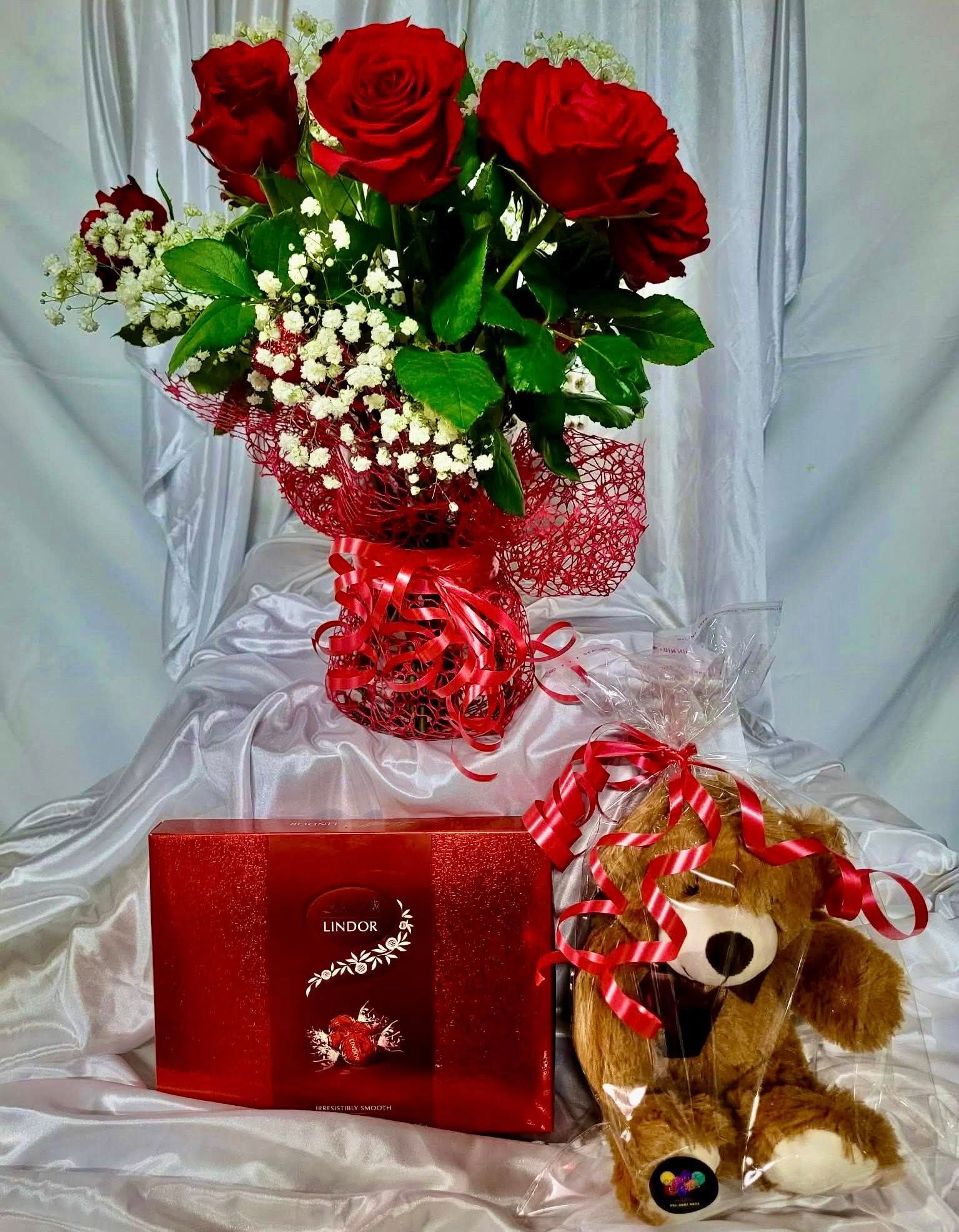 Bouquet of Red Roses, Red Gift Box, and Teddy Bear on a White Draped Surface — Creative Events Innisfail in Innisfail, QLD