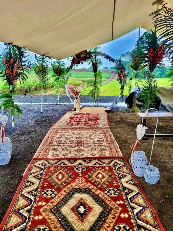 Outdoor Wedding Aisle With Patterned Rugs, Floral Decor, and Natural Background — Creative Events Innisfail in Babinda, QLD