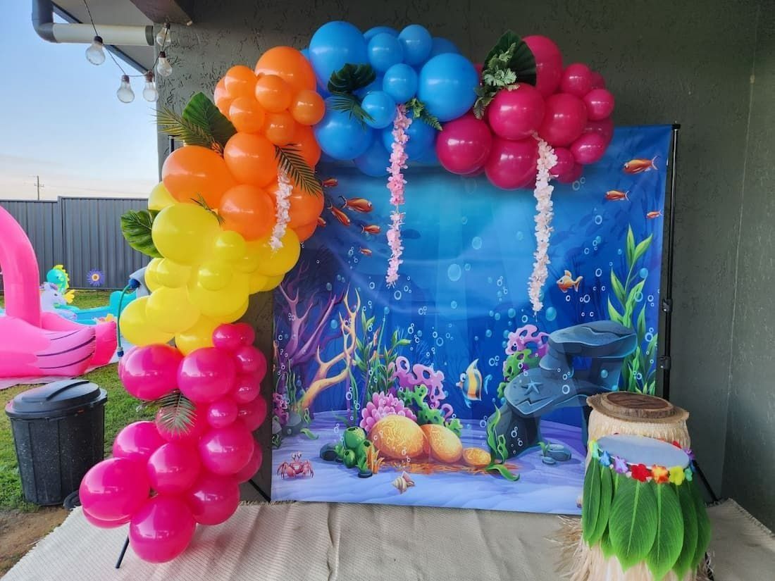 Colorful Balloon Arch With an Ocean Backdrop, Near a Pink Inflatable Flamingo — Creative Events Innisfail in Innisfail, QLD