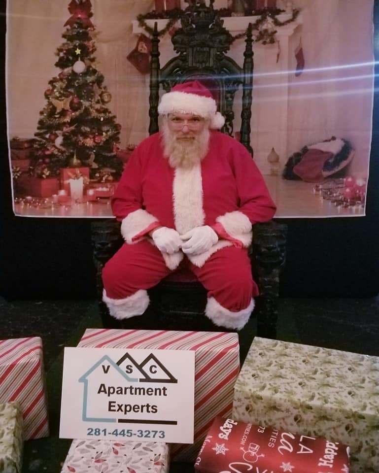 Santa claus is sitting in front of a sign that says apartment experts