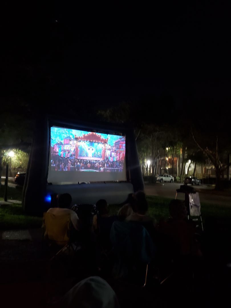 A group of people are sitting in front of a large screen watching a movie.