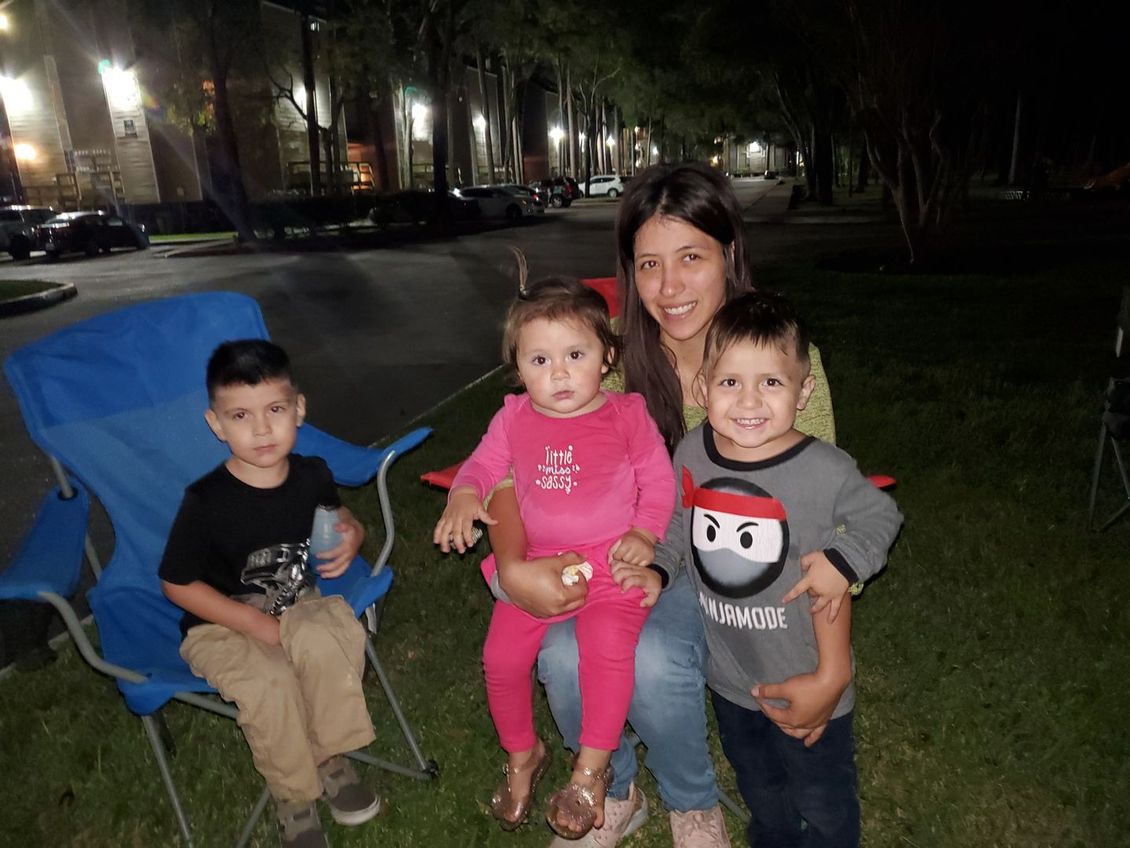 A woman is sitting in a chair with three children.