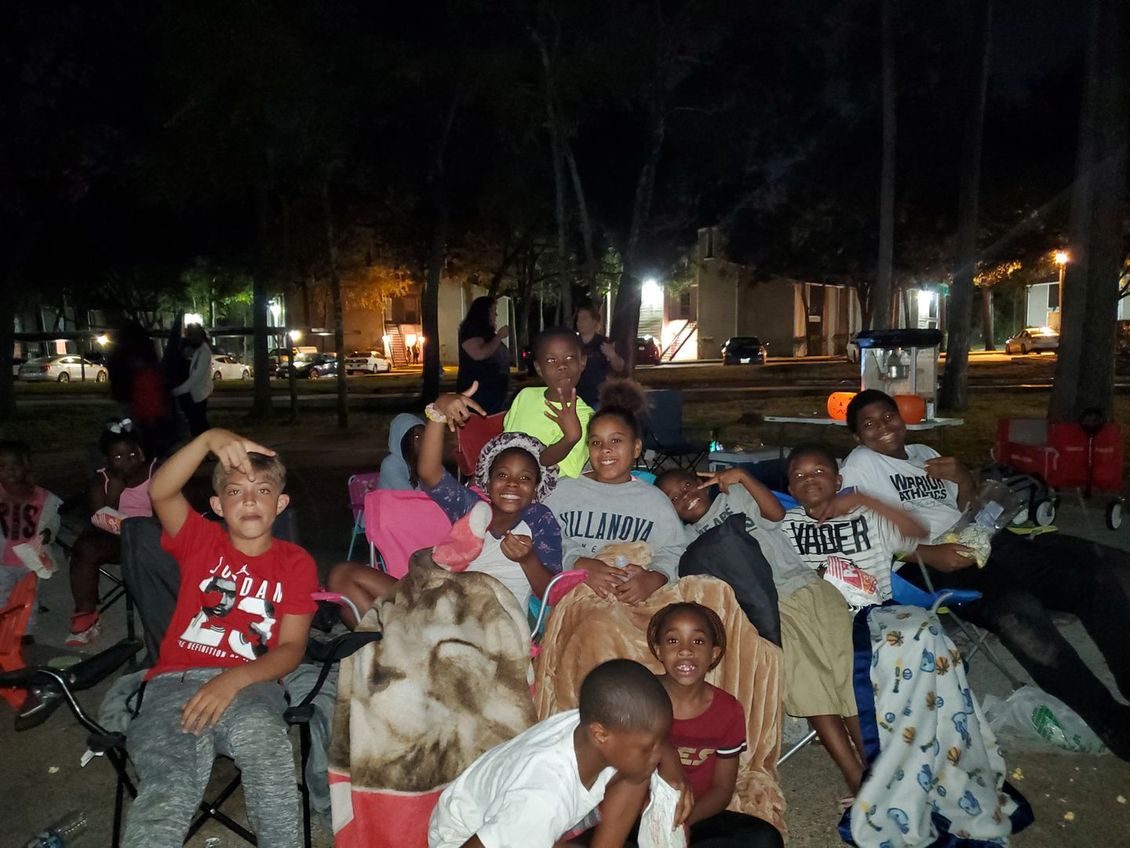 A group of children are sitting in chairs in a park at night.