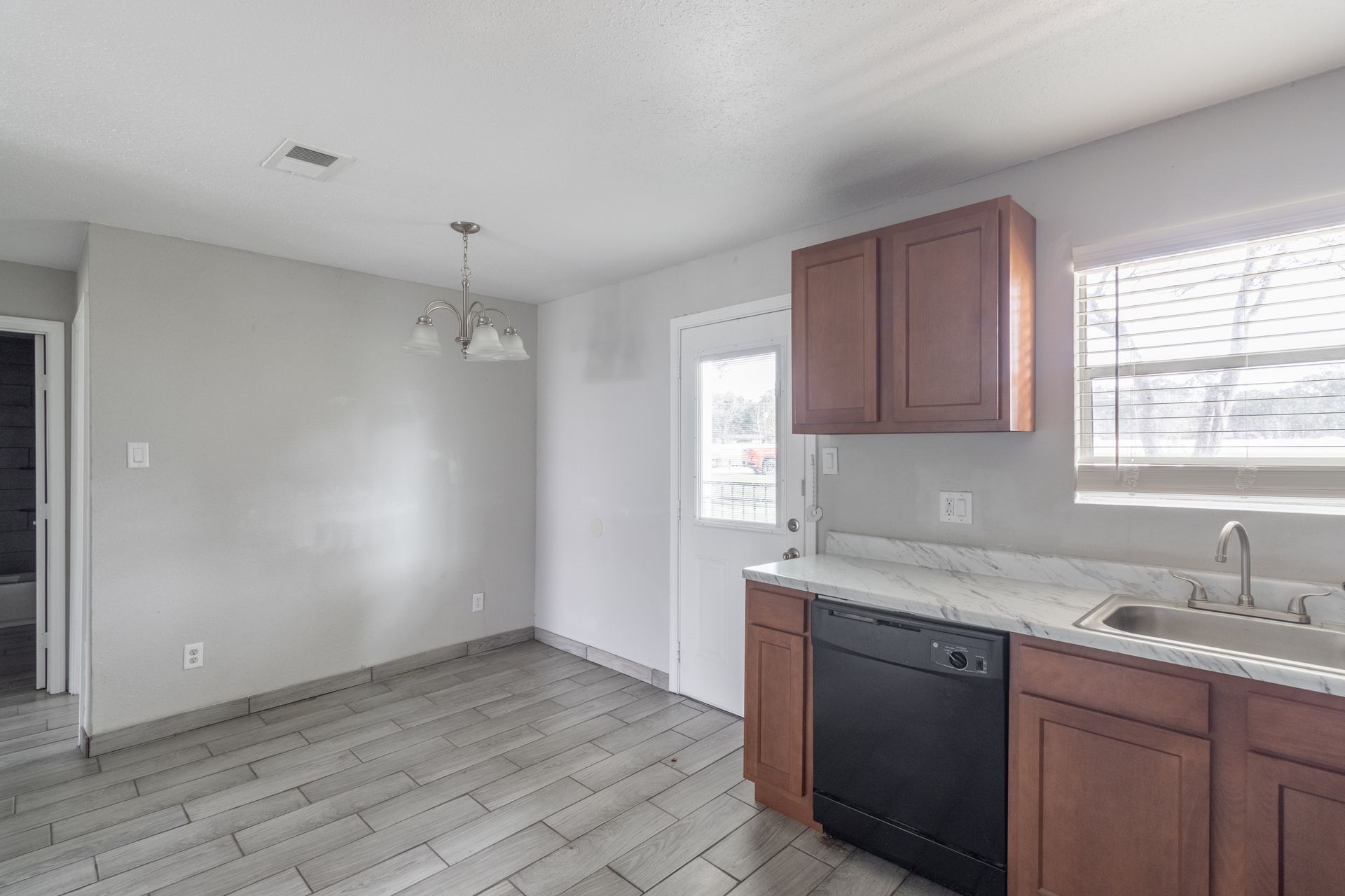  kitchen with wooden cabinets , a sink , and a dishwasher located in Monaco Villas Apartments .
