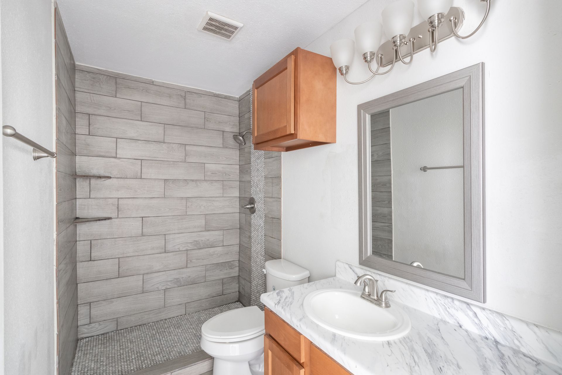 a bathroom with a toilet , sink , mirror and shower  inside of Monaco Villas Apartments.