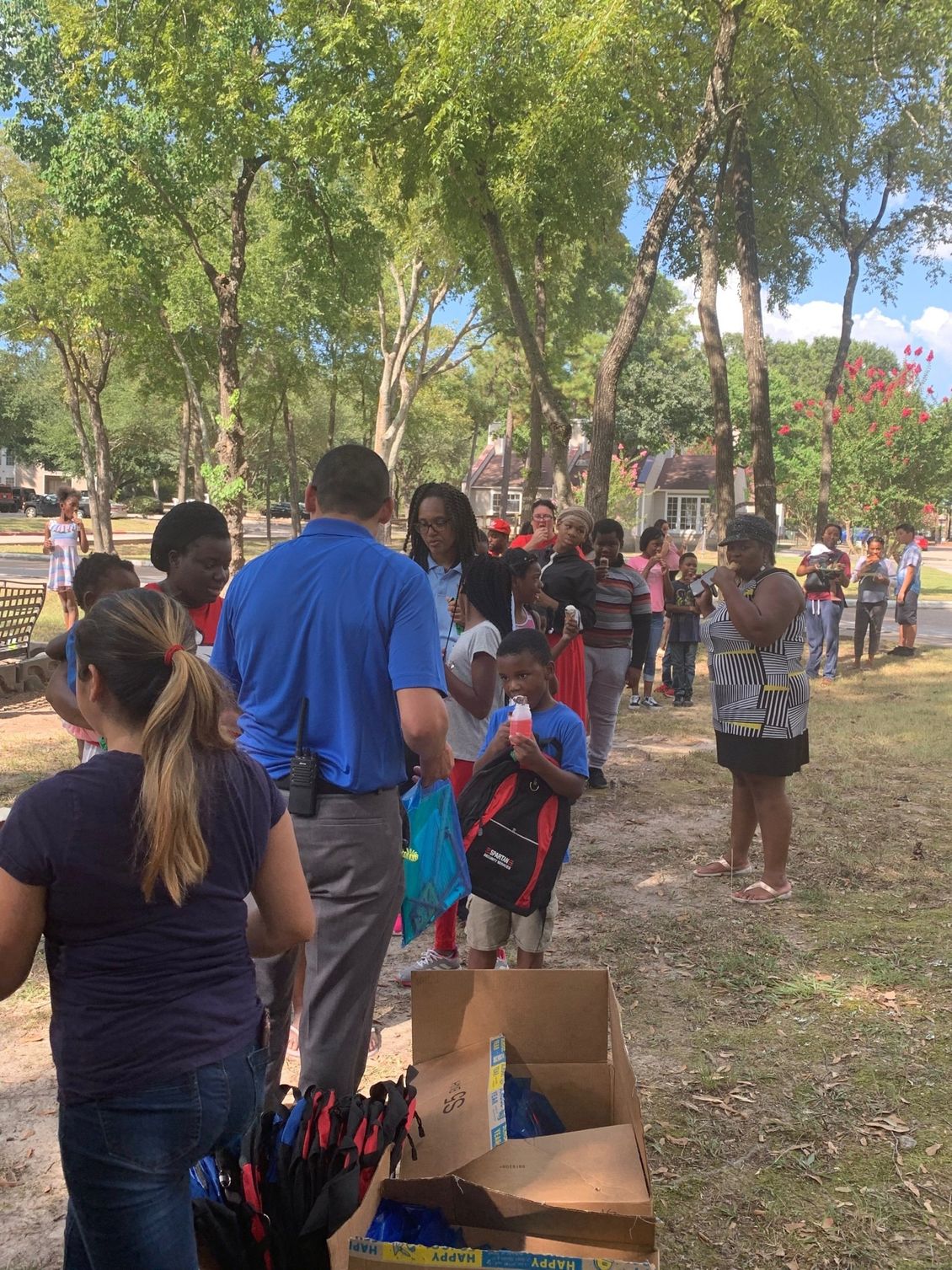 A group of people are standing in a line in a park.